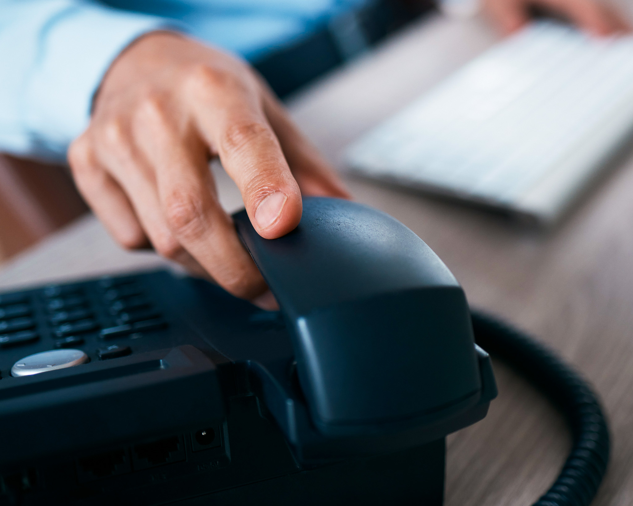 Mão sobre o telefone de mesa